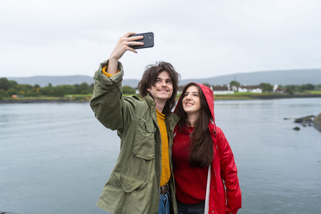 A couple taking a photo to create a customized Love From Ireland postcard