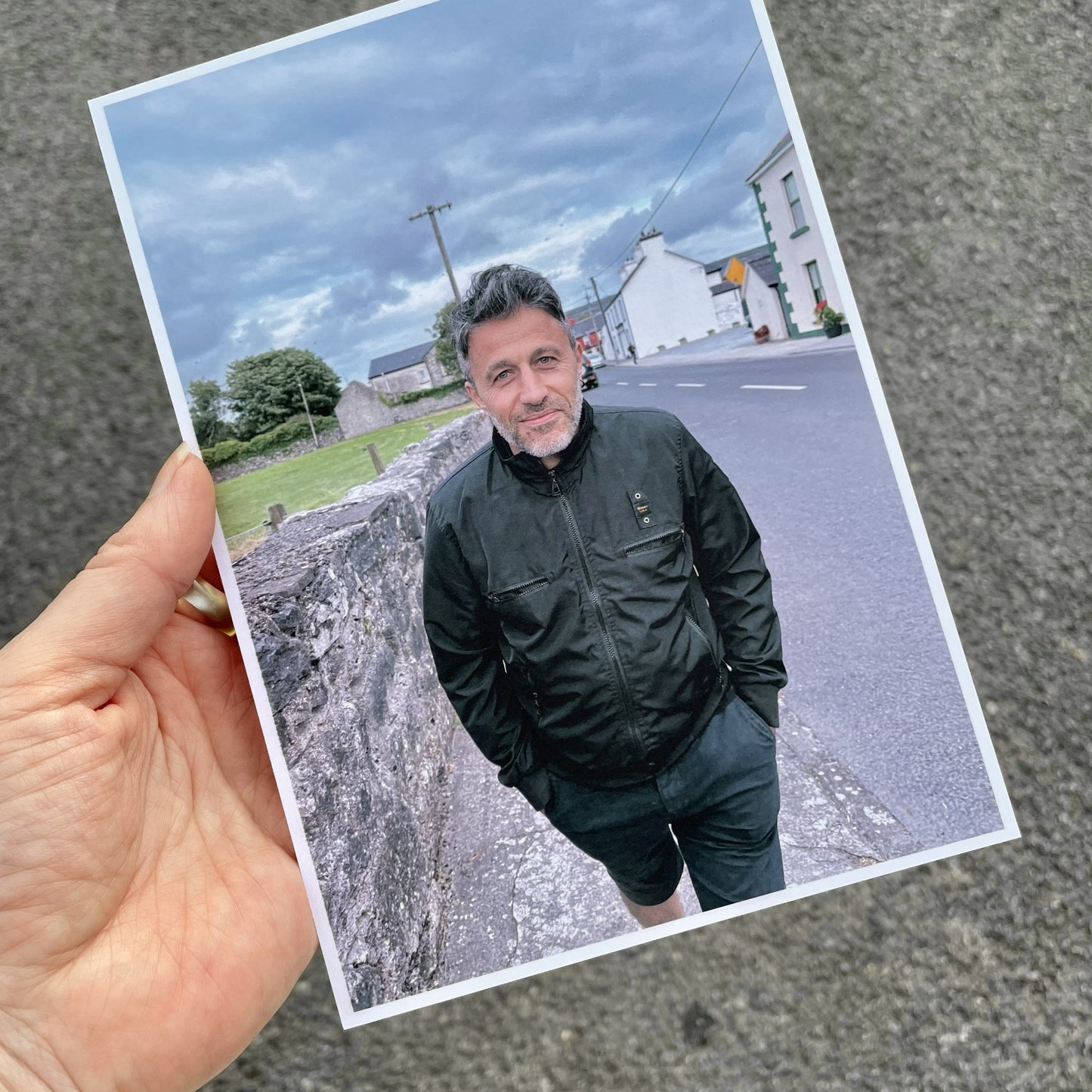 A hand holding a sample personalised photo postcard featuring a photo of a man walking down a street
