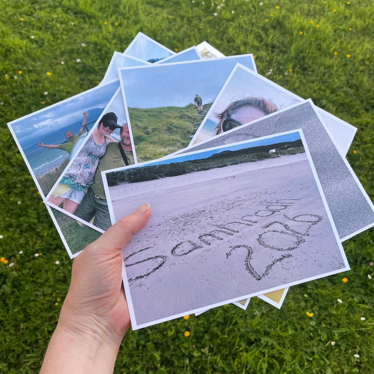 A hand holding a selection of photo postcards to illustrate what they look like