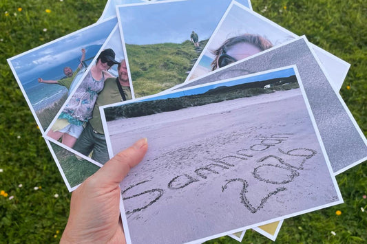 A hand holding a selection of photo postcards to illustrate what they look like