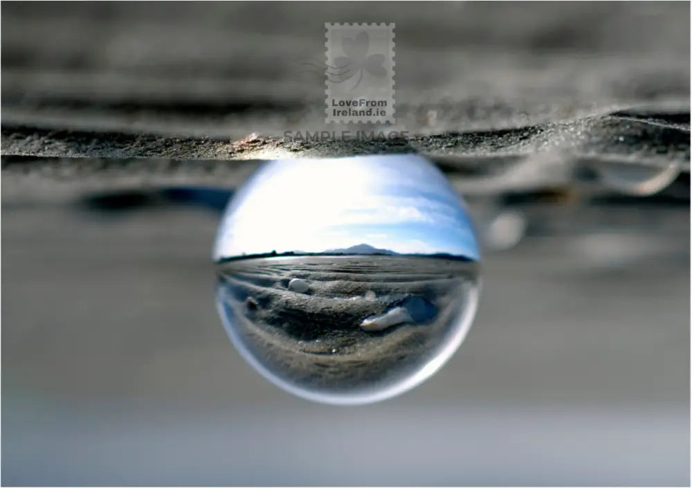 This photographic postcard depicts Muckish through a lens ball from the Boardwalk in Carrigart, County Donegal.